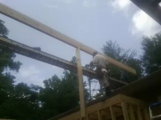 Carpenter setting a ridge beam over a new addition frame — Ice Dam Removal by Roofing Brothers in Farwell