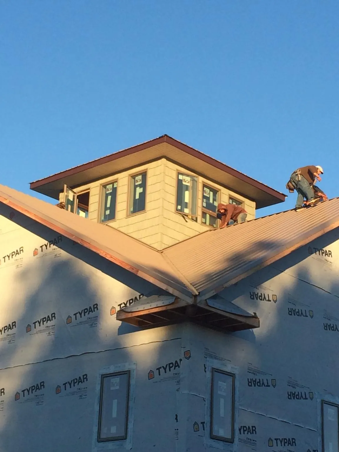 Roofers working around a rooftop cupola on a new metal roof at sunset — Roof Waterproofing in Farwell by Roofing Brothers